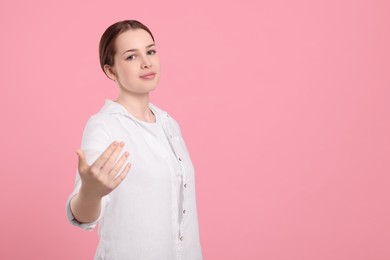 Photo of Beautiful woman inviting to come in against pink background, space for text