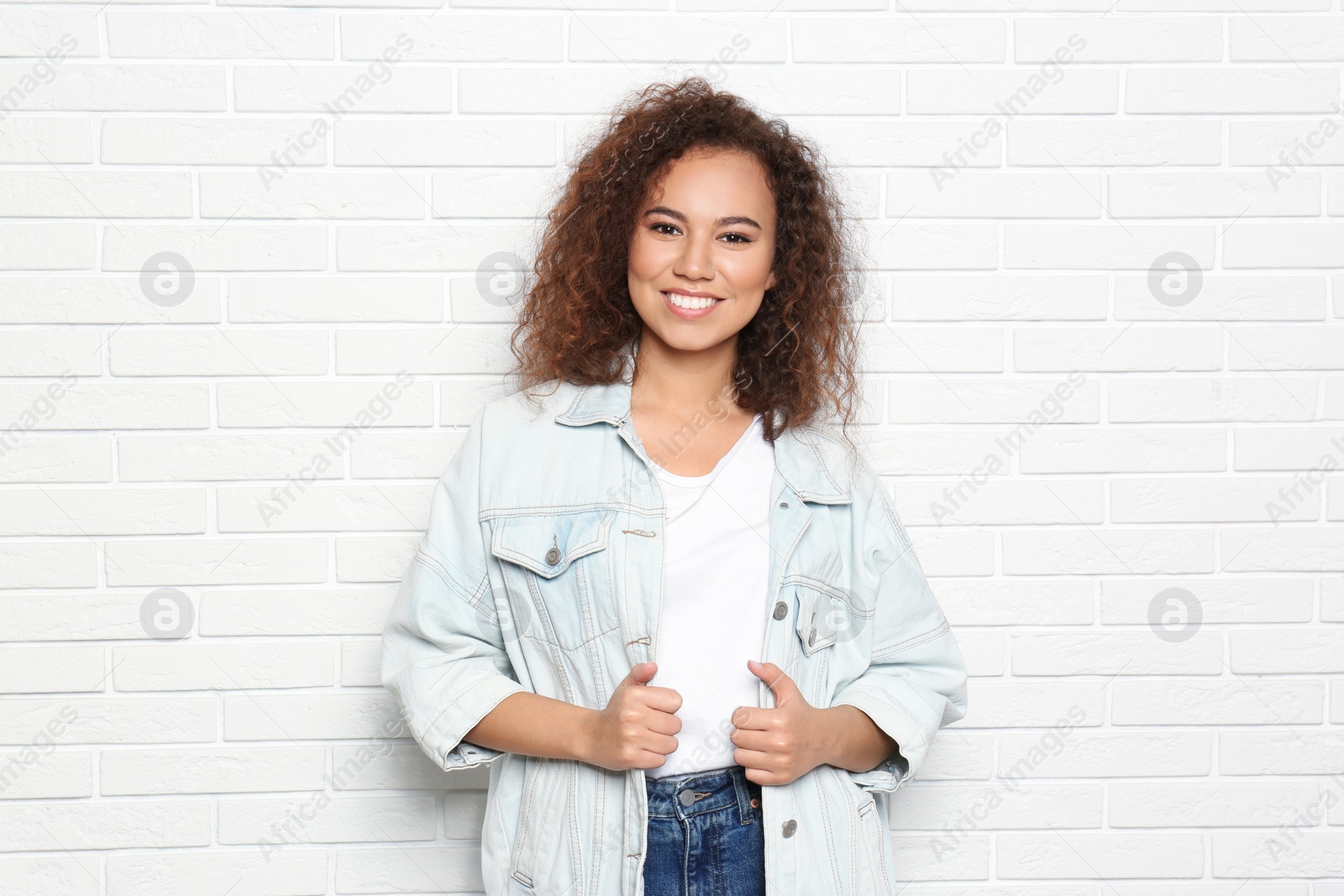 Photo of Young African-American woman with beautiful face near white brick wall