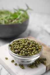 Photo of Glass bowl with mung beans and coaster on white textured table, closeup