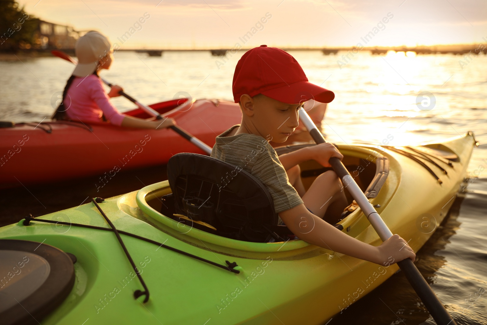 Photo of Children kayaking on river at sunset. Summer camp activity