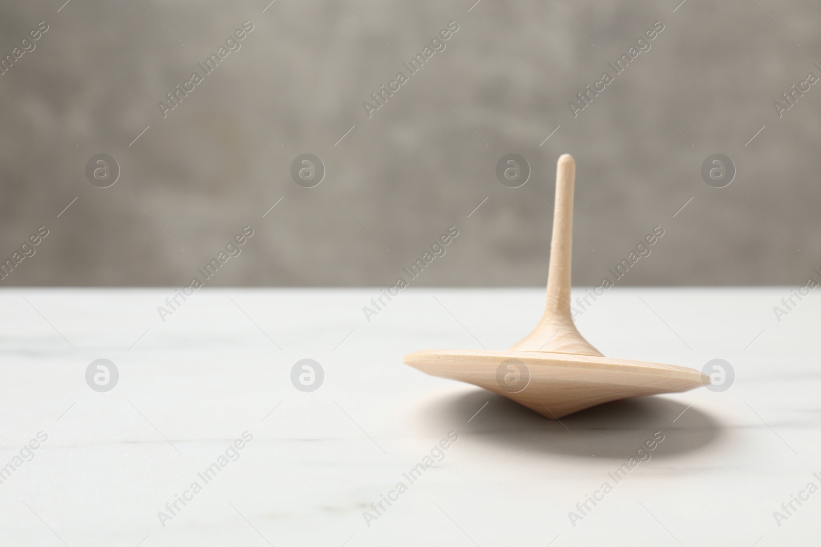 Photo of One spinning top on white table, closeup. Space for text