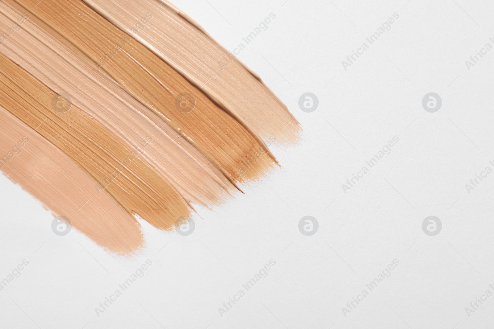 Photo of Samples of skin foundation on white background, top view. Space for text