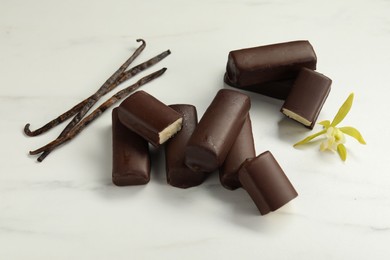 Photo of Glazed curd cheese bars, vanilla pods and flower on white table, flat lay