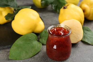 Delicious quince jam and fruits on grey table, closeup