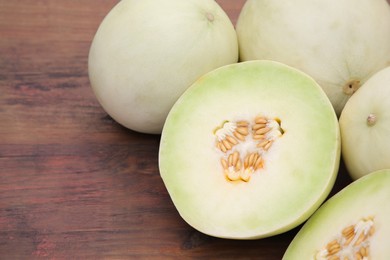 Whole and cut fresh ripe melons on wooden table. Space for text