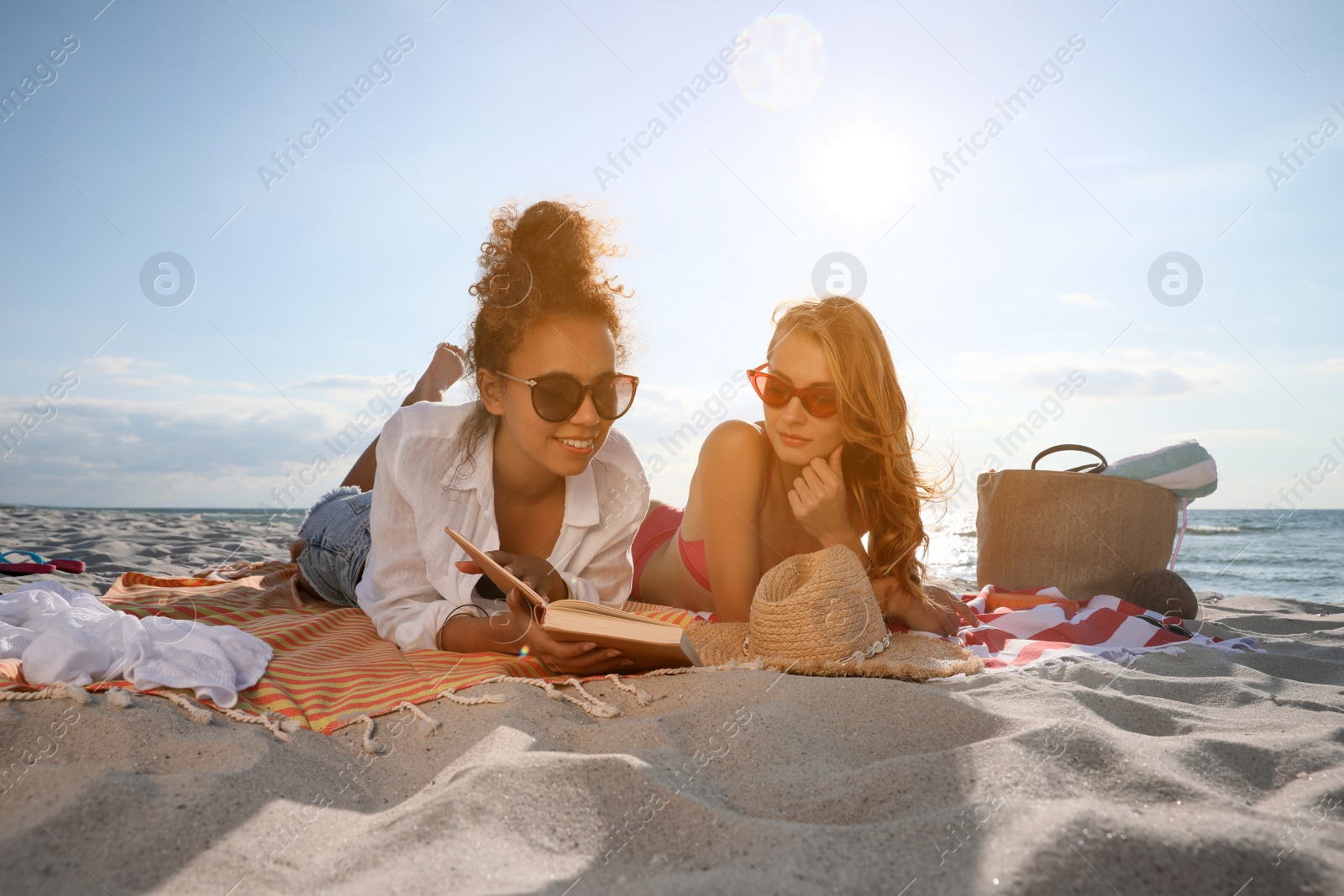 Photo of Friends lying on beach towels near sea