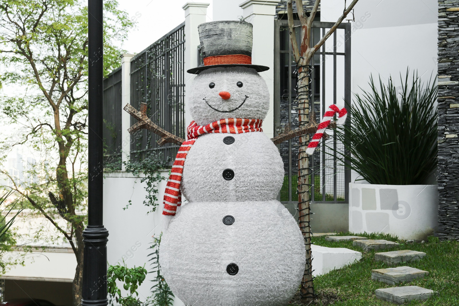 Photo of Funny snowman near house. Festive outdoor Christmas decoration