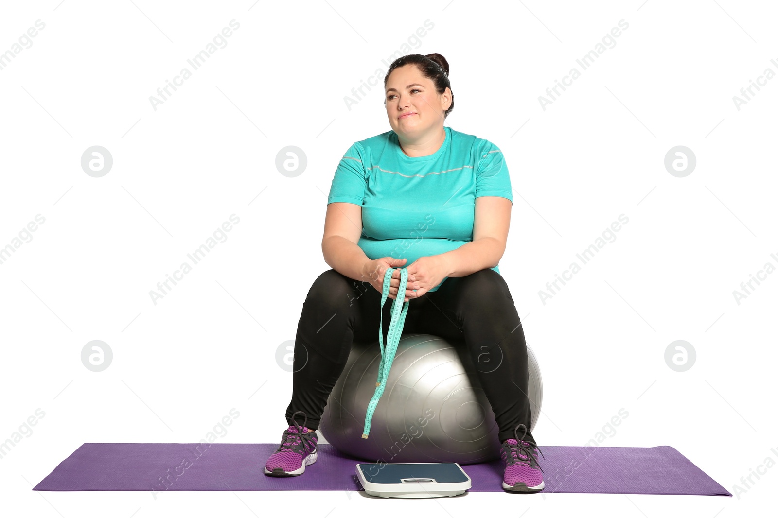 Photo of Overweight woman with scale, measuring tape and fitness ball on white background