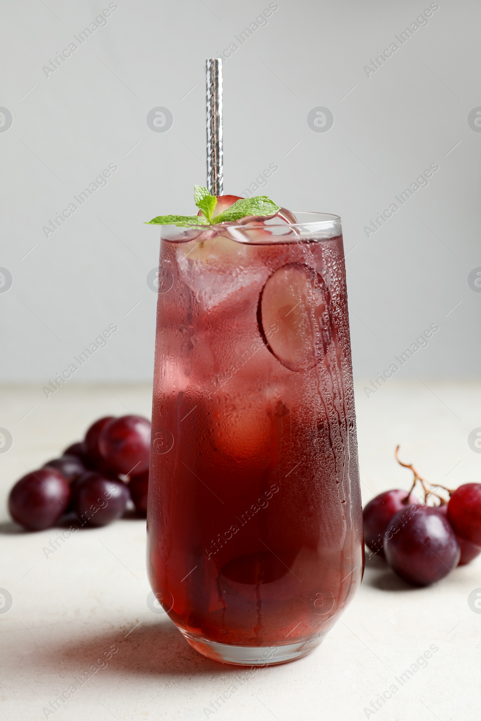 Photo of Delicious grape soda water with mint on white table. Refreshing drink