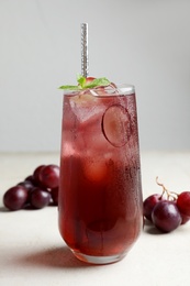 Photo of Delicious grape soda water with mint on white table. Refreshing drink