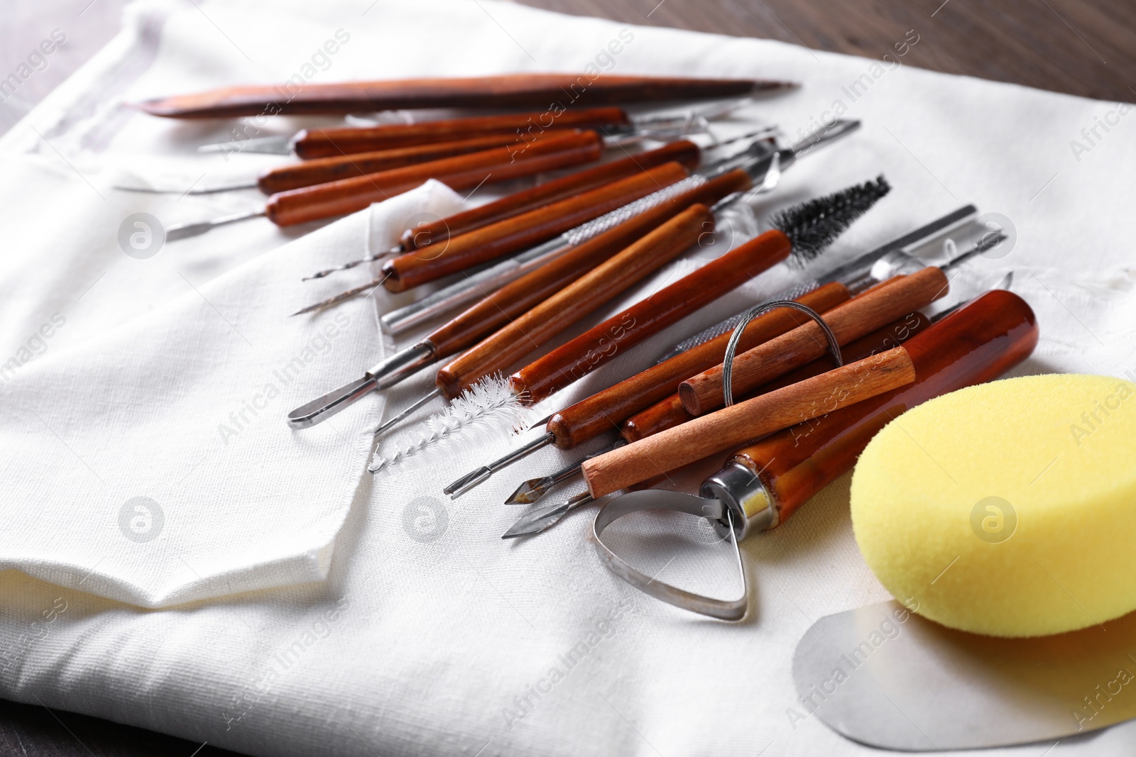 Photo of Set of different clay crafting tools on wooden table, closeup
