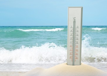 Image of Weather thermometer on sandy beach near sea, space for text
