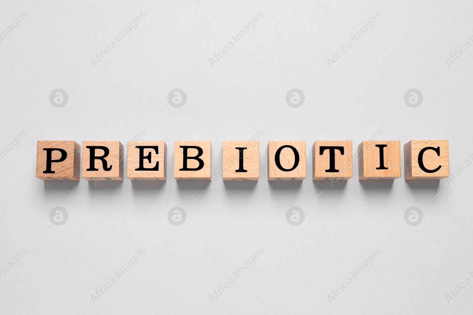 Photo of Wooden cubes with word Prebiotic on white background, top view