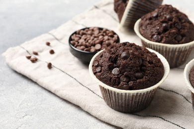 Photo of Tasty chocolate muffins and cloth on table, closeup. Space for text