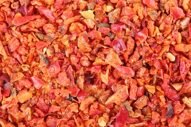 Photo of Aromatic spice. Red chili pepper flakes as background, top view