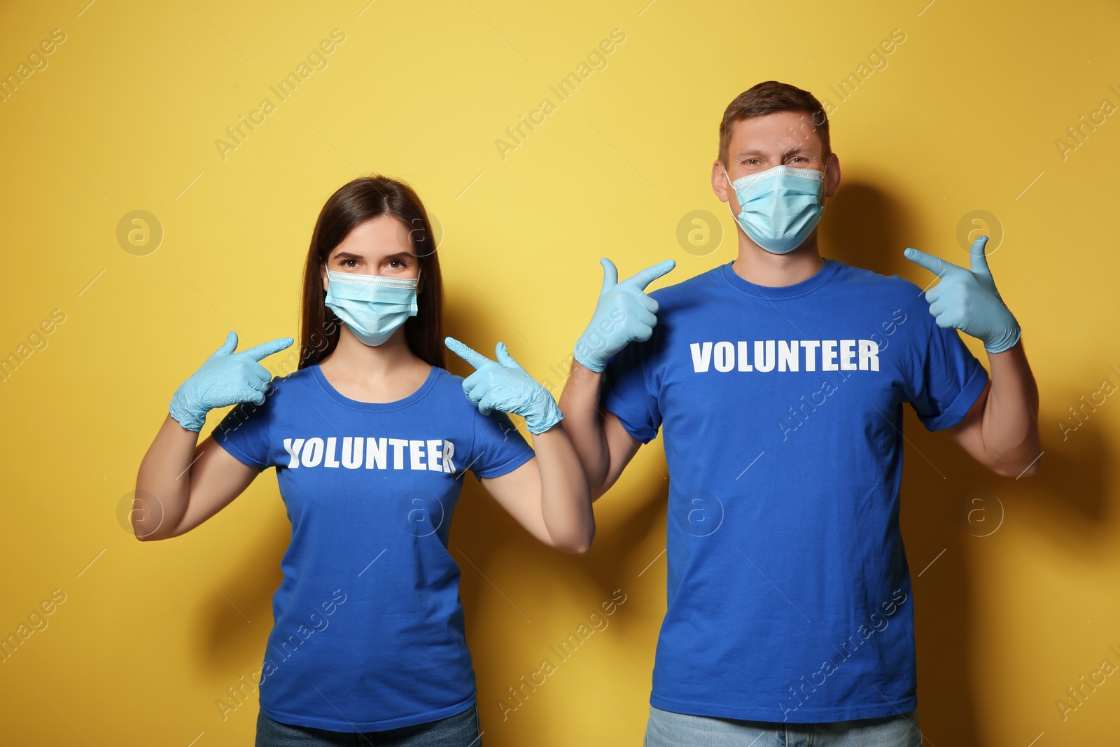 Photo of Volunteers in masks and gloves on yellow background. Protective measures during coronavirus quarantine