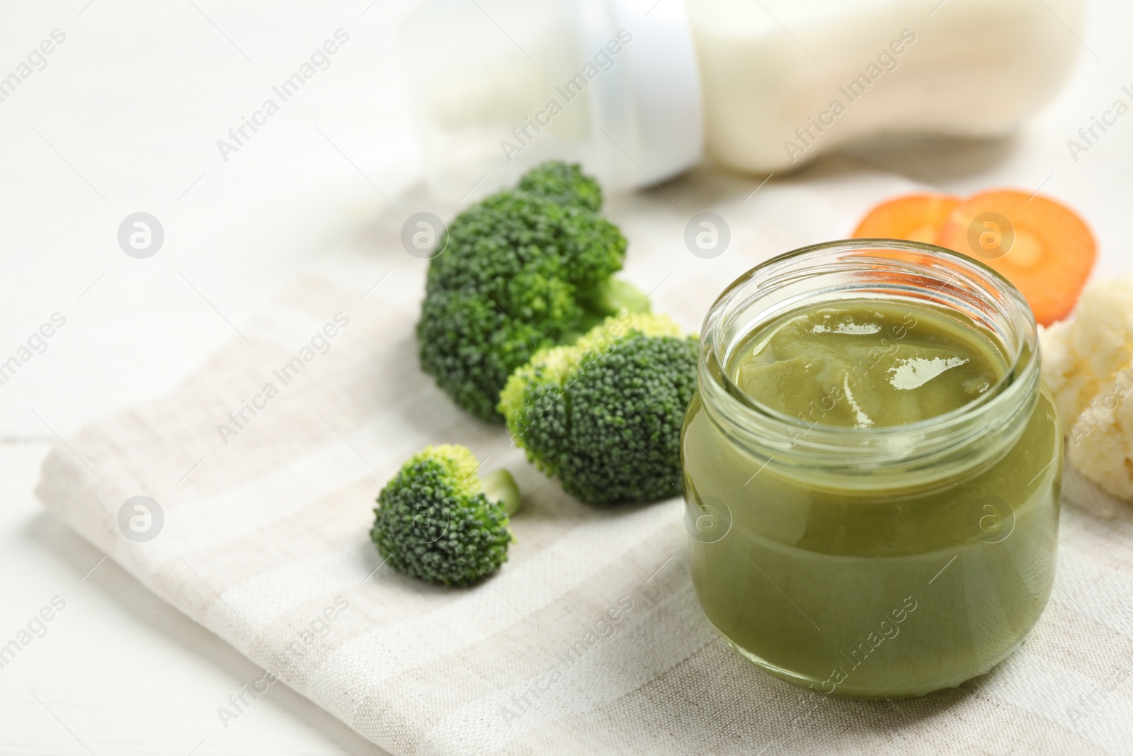 Photo of Healthy baby food and fresh ingredients on white table. Space for text