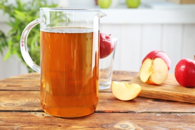 Photo of Jug with fresh apple juice on wooden table