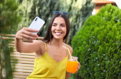 Beautiful woman taking selfie in deckchair at garden