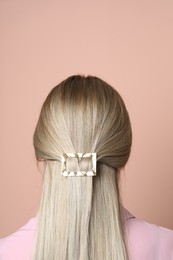Photo of Young woman with beautiful gold hair clip on pink background, back view
