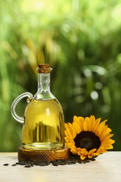 Photo of Sunflower cooking oil, seeds and yellow flower on white wooden table outdoors