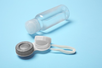 Contact lens case, tweezers and bottle of solution on color background