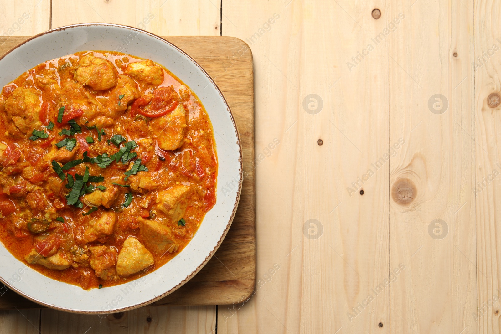 Photo of Delicious chicken curry on wooden table, top view. Space for text