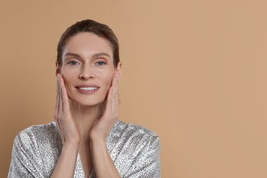 Photo of Woman massaging her face on beige background. Space for text