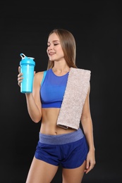 Photo of Portrait of woman with bottle of protein shake and towel on black background