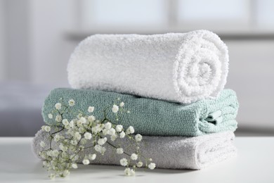Photo of Stack of folded colorful towels with flowers on white table indoors, closeup