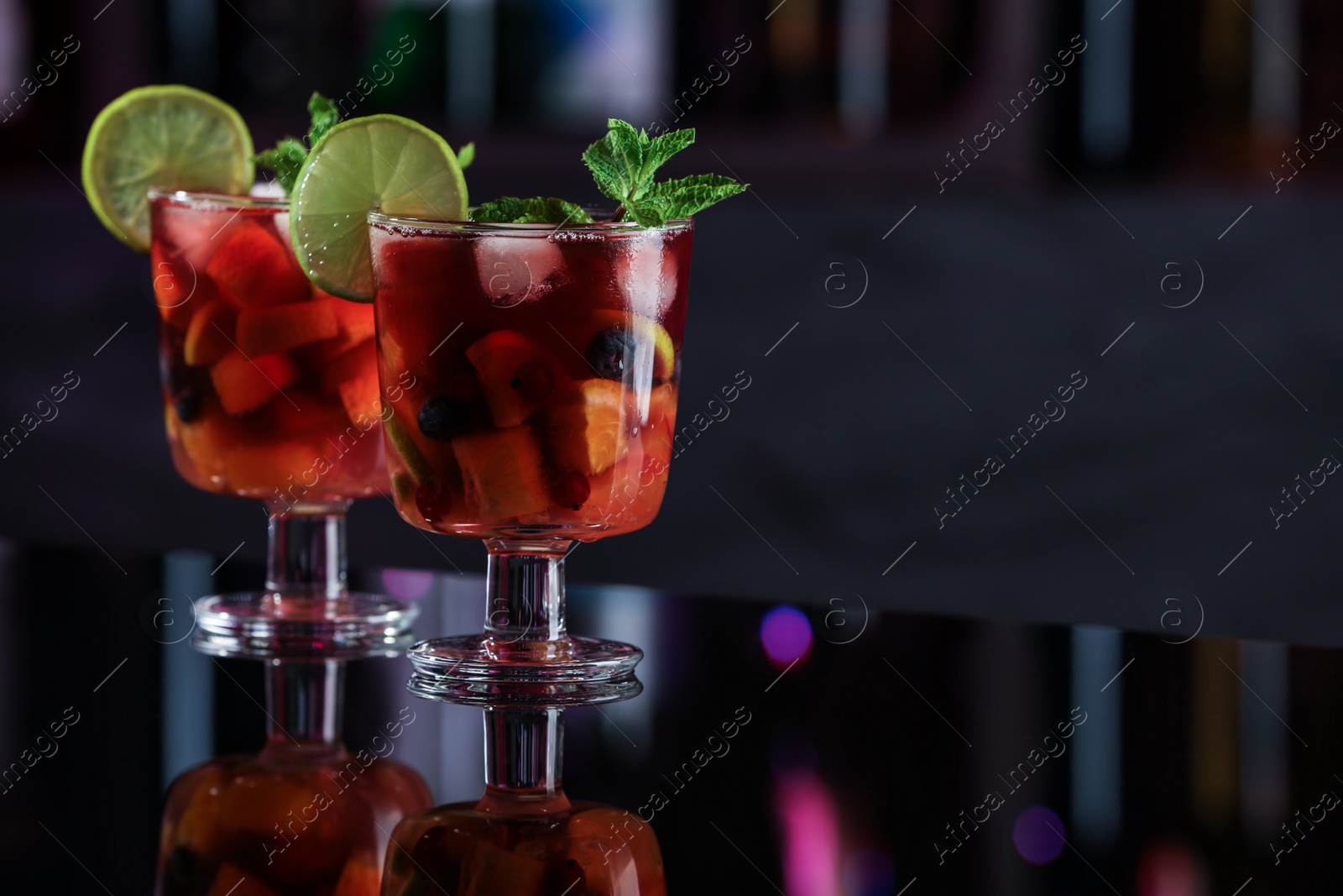 Photo of Delicious sangria cocktail on black table in bar. Space for text