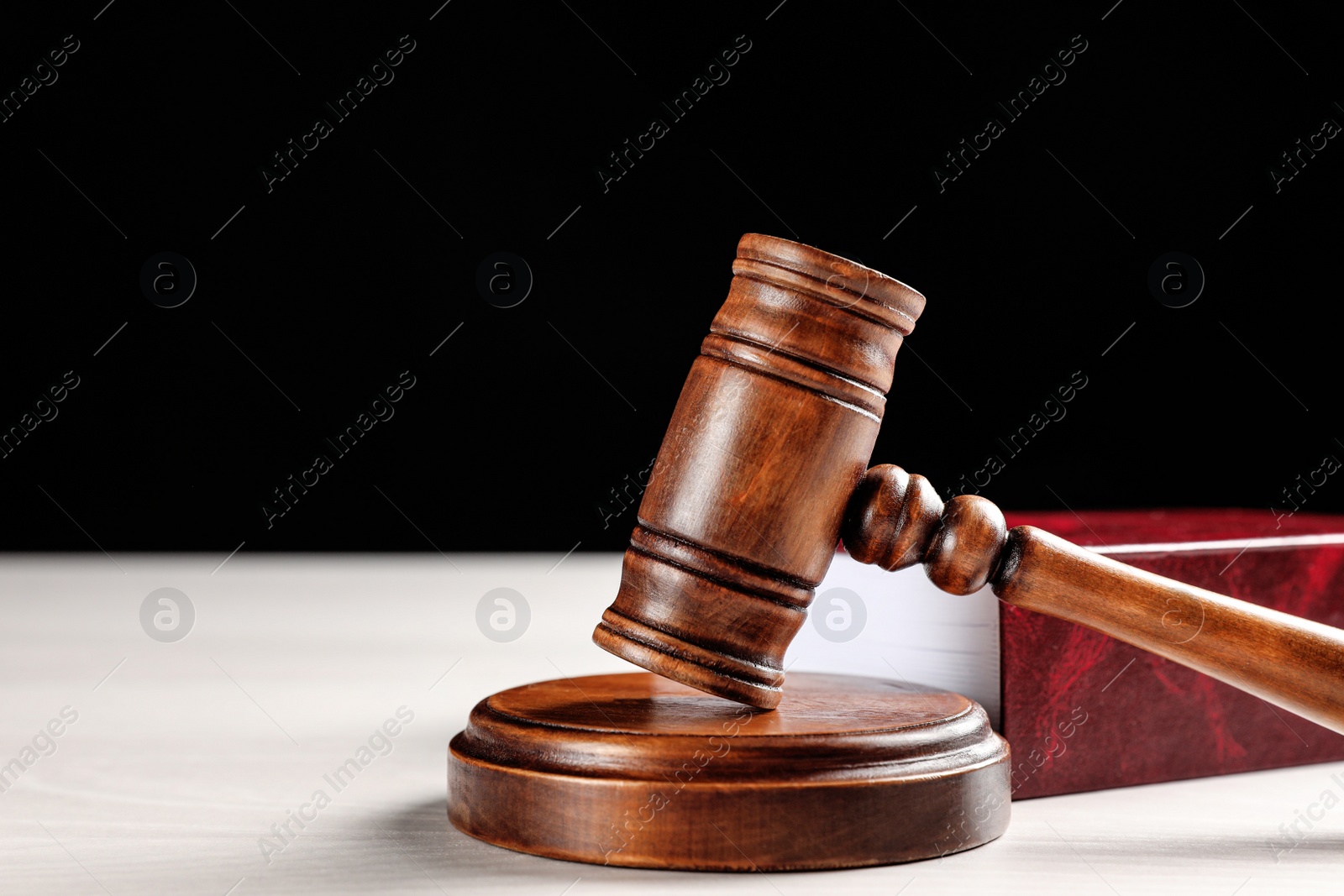 Photo of Judge's gavel and book on white table against black background, space for text. Criminal law concept