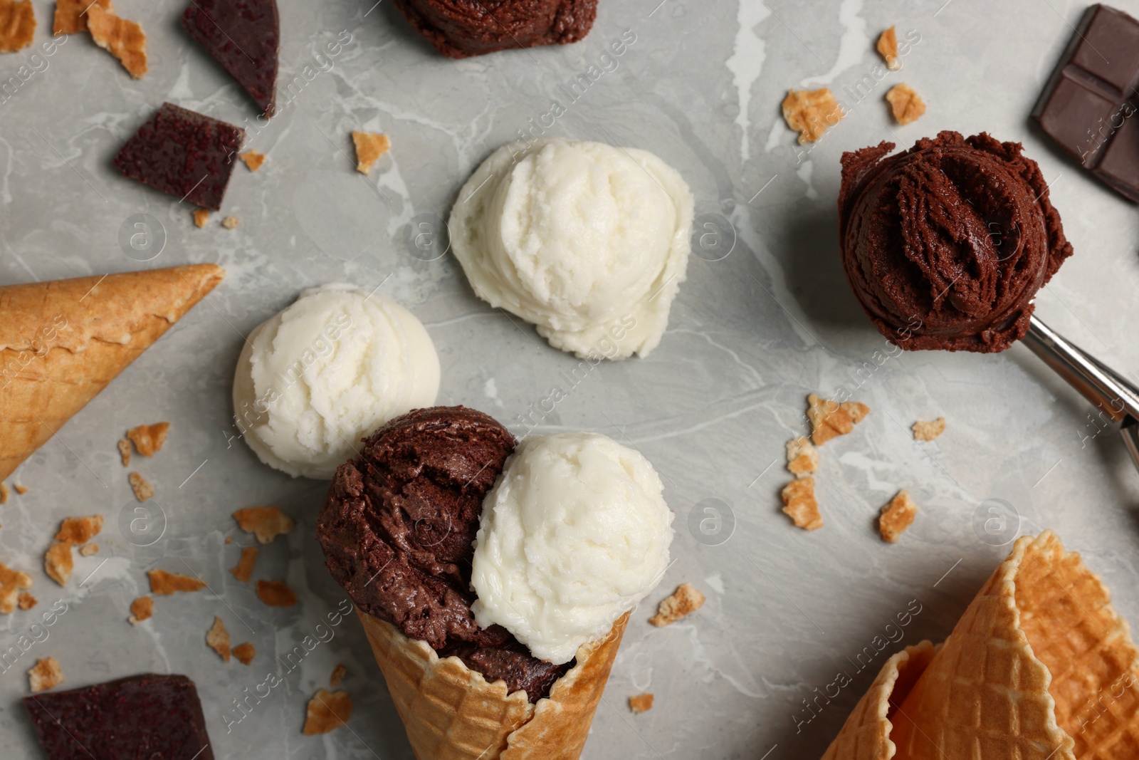 Photo of Flat lay composition with tasty ice cream scoops, pieces of chocolate and waffle cones on light marble table