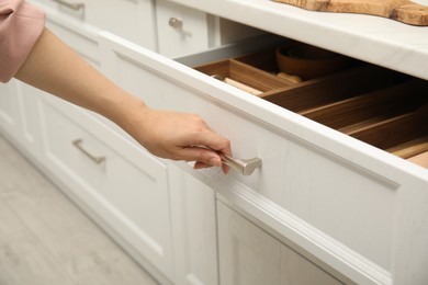 Woman opening drawer in kitchen, closeup view