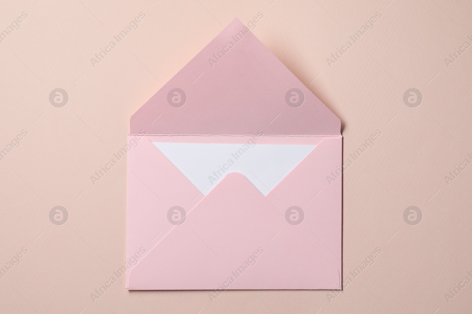 Photo of Letter envelope with card on beige background, top view