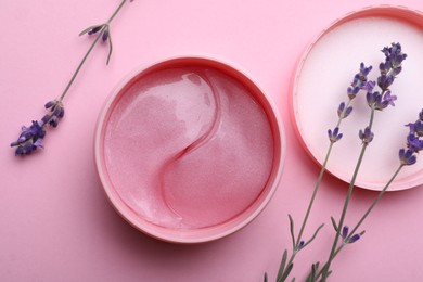 Photo of Package of under eye patches and lavender flowers on pink background, flat lay. Cosmetic product