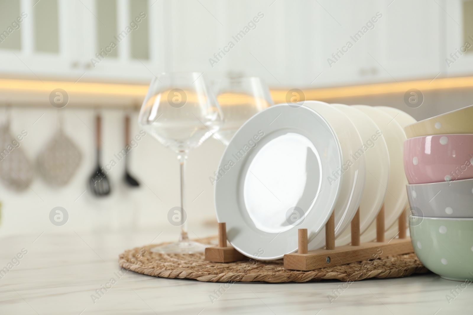 Photo of Clean plates, bowls and glasses on white marble table in kitchen, space for text