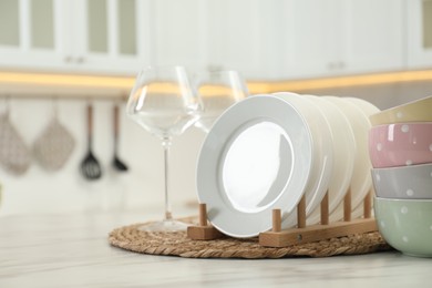 Clean plates, bowls and glasses on white marble table in kitchen, space for text