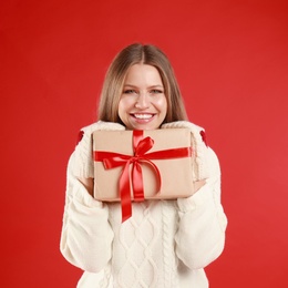 Photo of Happy young woman with Christmas gift on red background