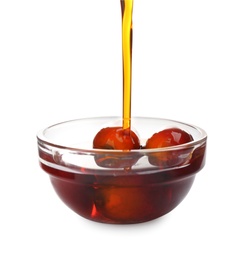 Palm oil pouring into glass bowl with fruits isolated on white