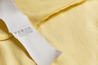 Clothing label on beautiful yellow garment, closeup. Space for text