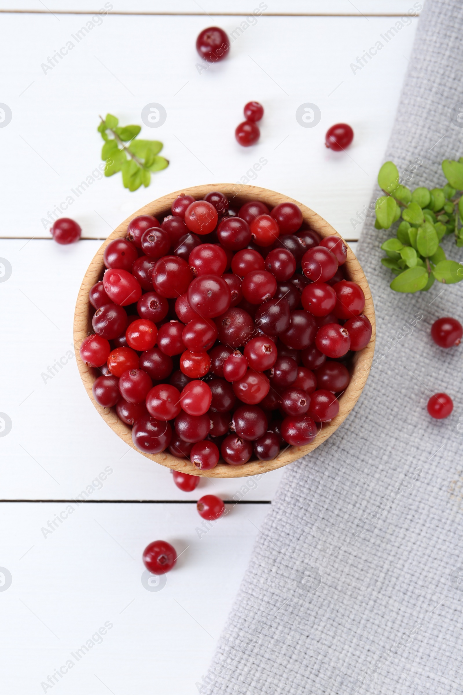 Photo of Fresh ripe cranberries and branches on white wooden table, top view