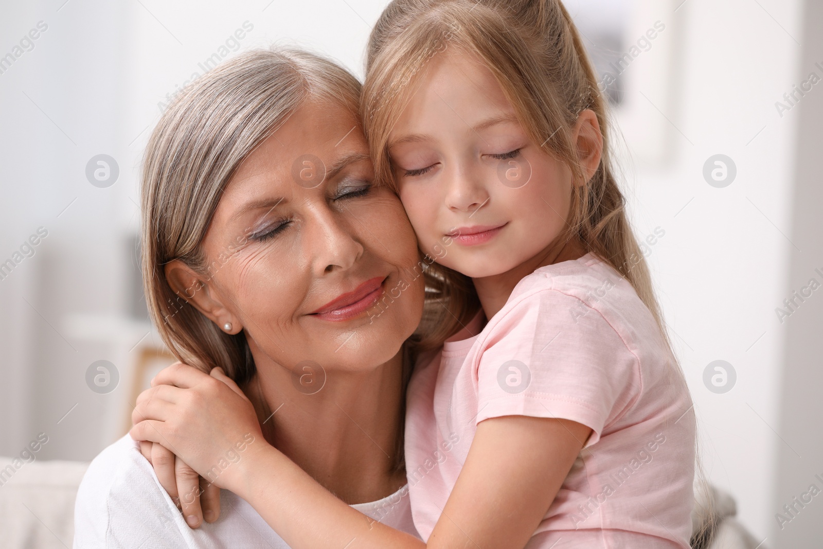 Photo of Happy grandmother hugging her granddaughter at home