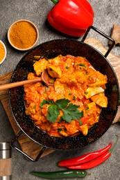 Delicious chicken curry and ingredients on grey table, flat lay