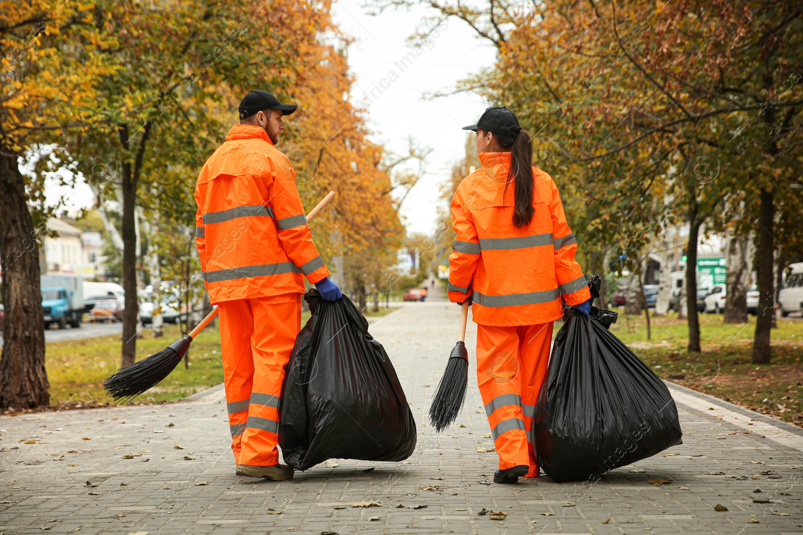 Photo of Street cleaner with brooms and garbage bags outdoors on autumn day, back view