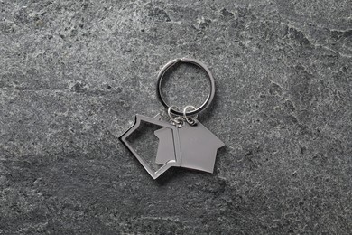 Metal keychain in shape of houses on grey textured table, top view
