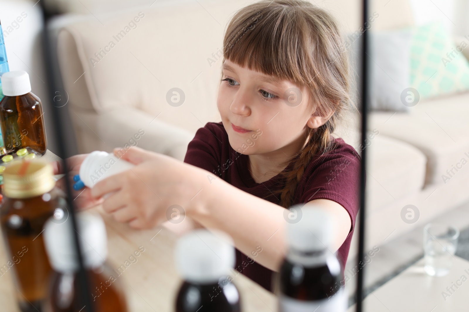 Photo of Little child taking pills from shelf at home. Danger of medicament intoxication