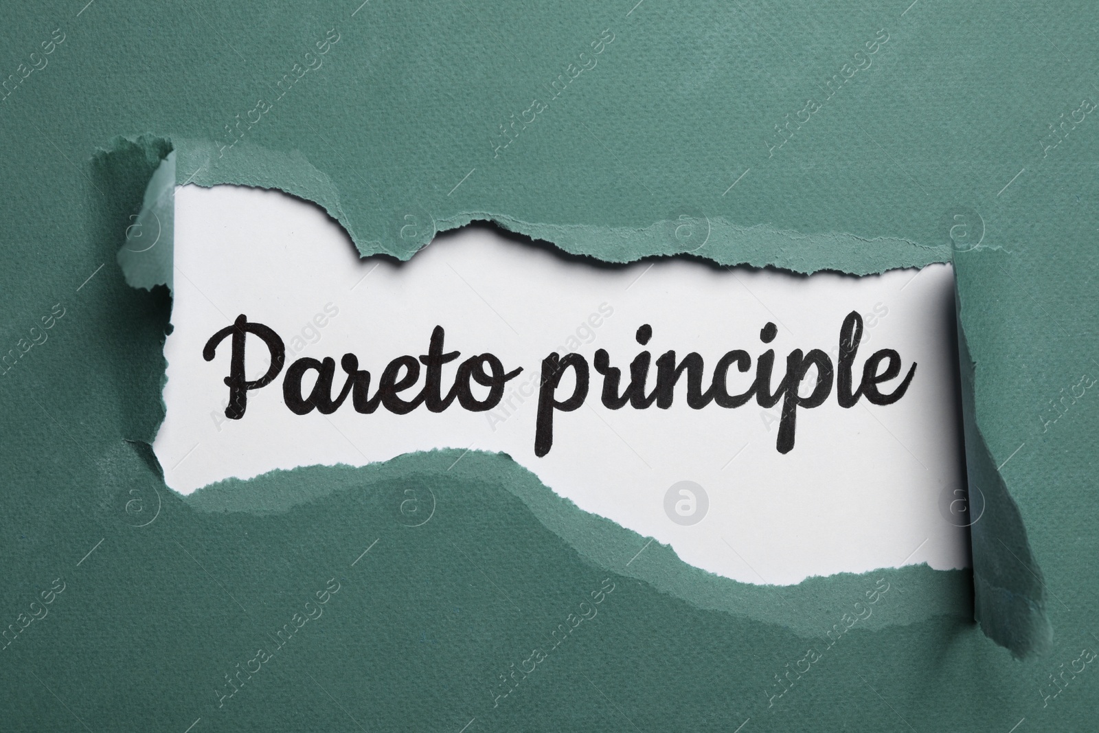 Photo of Words PARETO PRINCIPLE on white background, view through hole in green paper