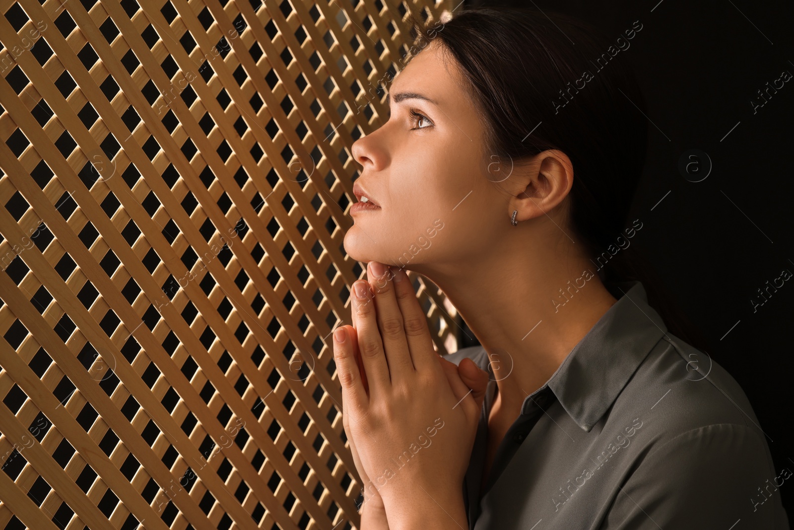 Photo of Woman praying to God during confession in booth