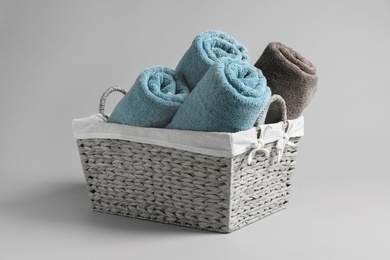 Basket with rolled towels on light background